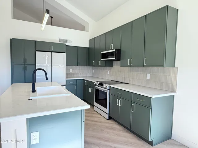 a kitchen with stainless steel appliances a sink a stove top oven a counter space and cabinets