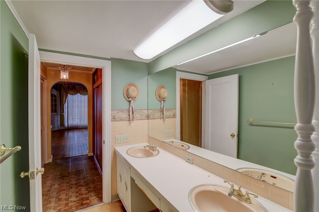 45555 North Ridge Road Amherst, OH 44001 - Photo 17 of 36 Owner's Bathroom with ornamental molding, tile walls, and dual bowl vanity