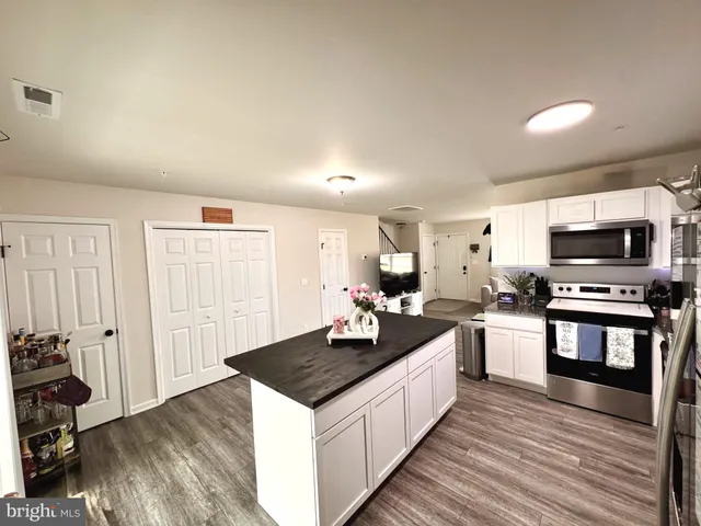 a kitchen with granite countertop a stove top oven a sink dishwasher and a refrigerator with wooden floor