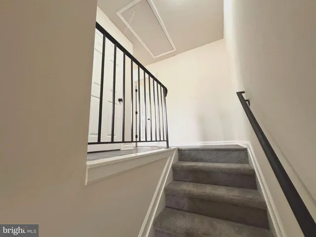 a view of staircase with white walls and a rug