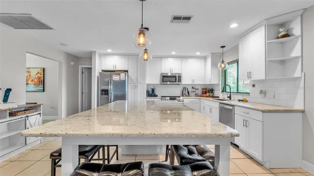 a kitchen with granite countertop a table chairs stainless steel appliances and cabinets