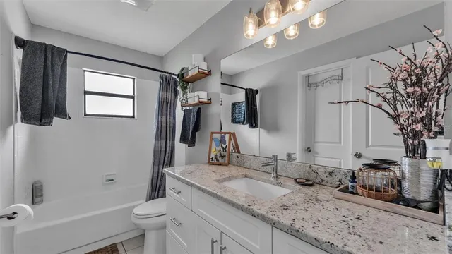 a bathroom with a granite countertop sink a toilet a mirror and shower