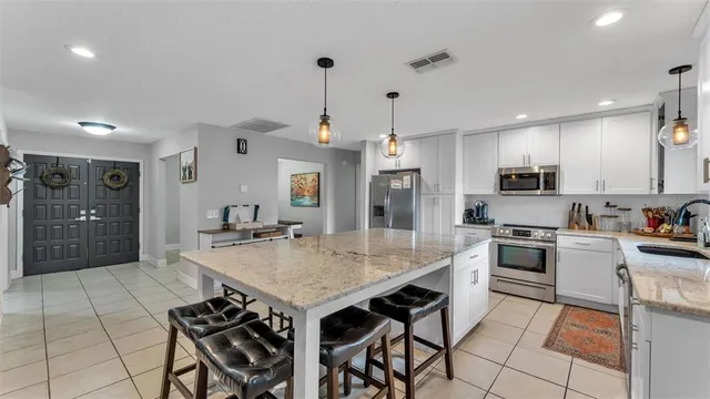 a kitchen with granite countertop a stove a sink dishwasher a refrigerator and white cabinets with wooden floor