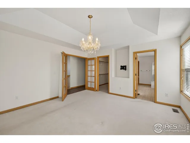 a view of an empty room with window and chandelier