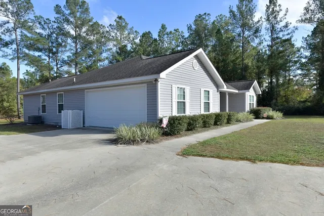 a view of a house with a yard plants and large tree
