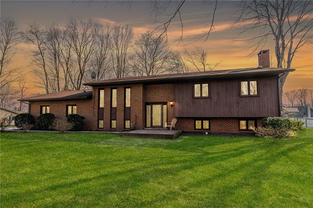 a view of a brick house with a big yard and large trees