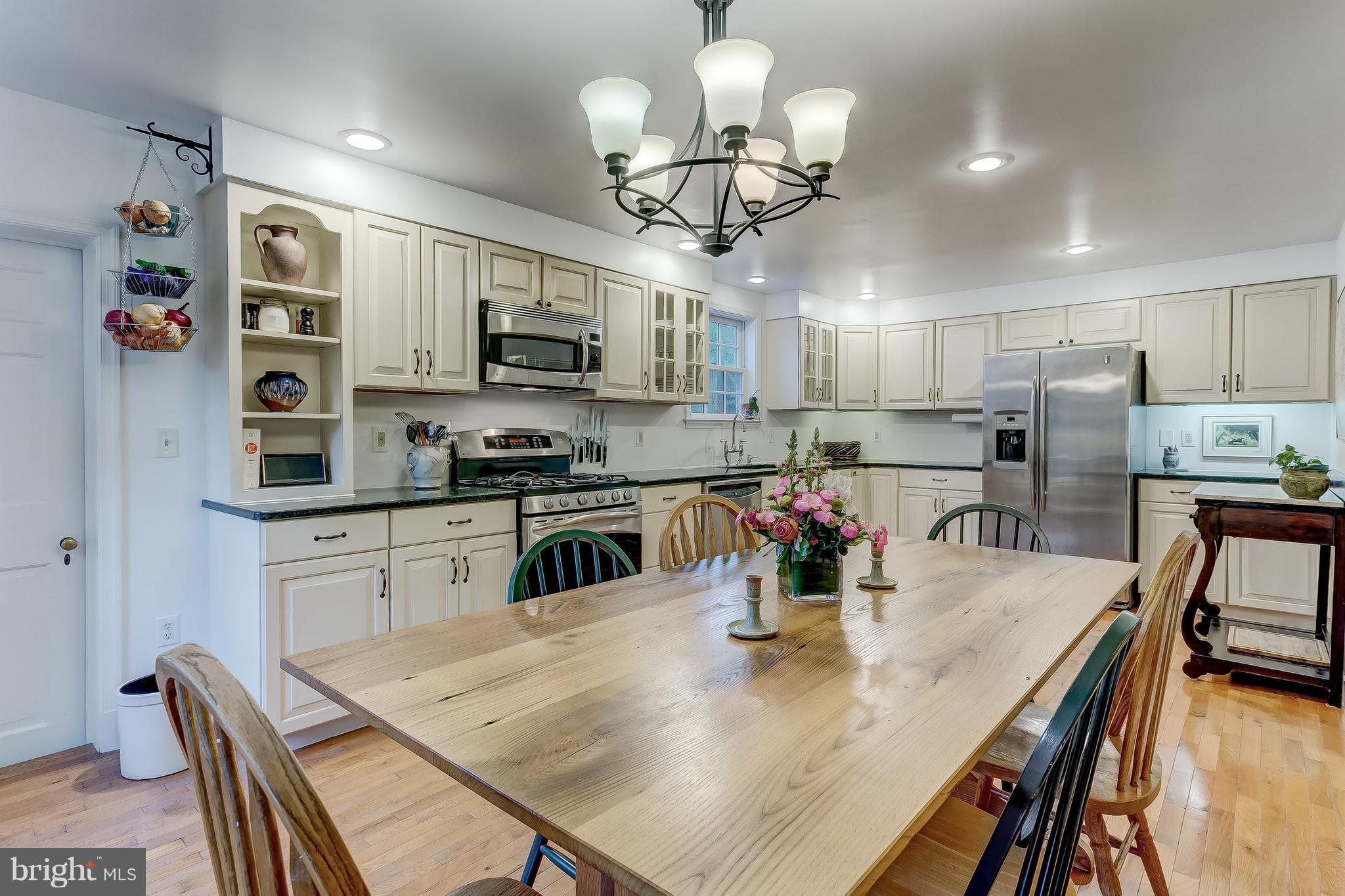 14737 Carroll Road Phoenix, MD 21131 - Photo 8 of 30 a kitchen with stainless steel appliances granite countertop a sink dishwasher a stove a microwave oven a dining table and chairs with wooden floor