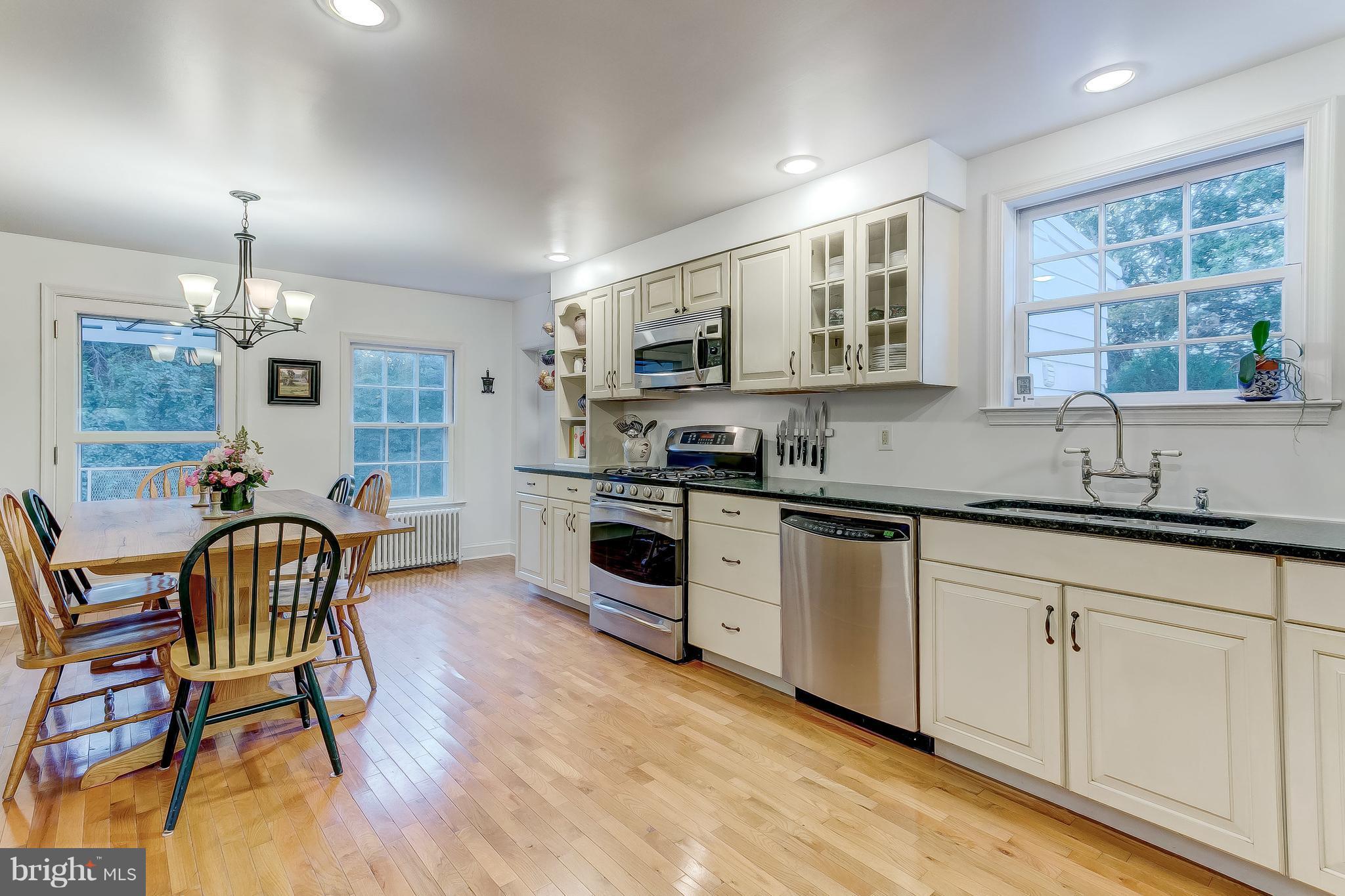 14737 Carroll Road Phoenix, MD 21131 - Photo 9 of 30 a kitchen with stainless steel appliances kitchen island granite countertop a stove a sink a dining table and chairs with wooden floor