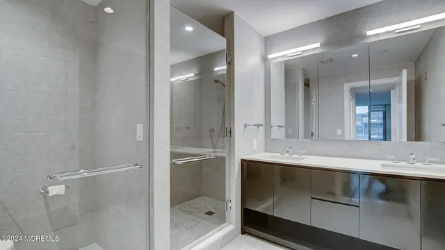 a bathroom with a granite countertop sink a mirror and shower