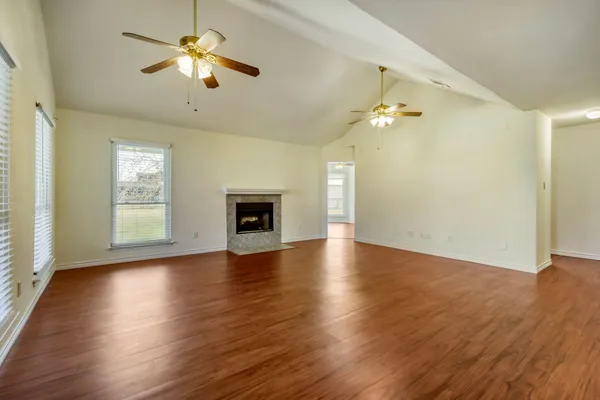 a view of empty room with wooden floor and fan