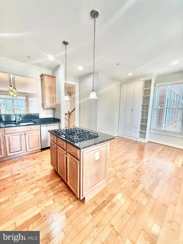 a large kitchen with kitchen island granite countertop a stove a sink and a wooden floors