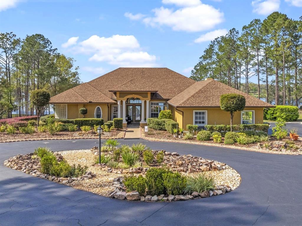 22527 Lake Seneca Road Eustis, FL 32736 - Photo 1 of 1 a front view of a house with swimming pool having outdoor seating