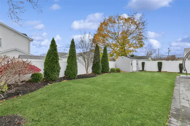 a backyard of a house with plants and large tree