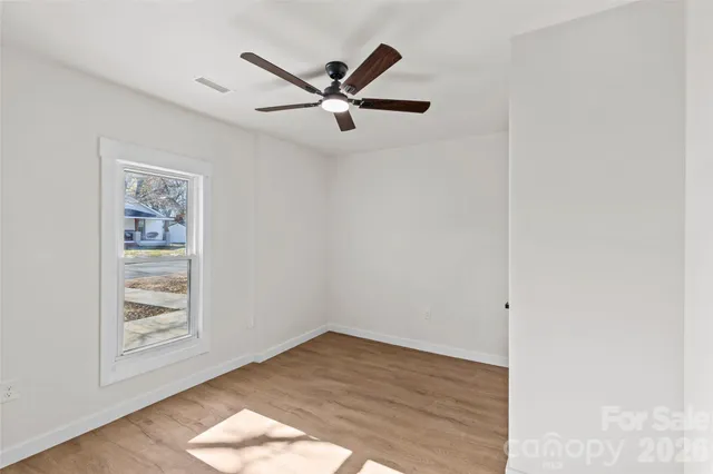 an empty room with wooden floor closet and windows