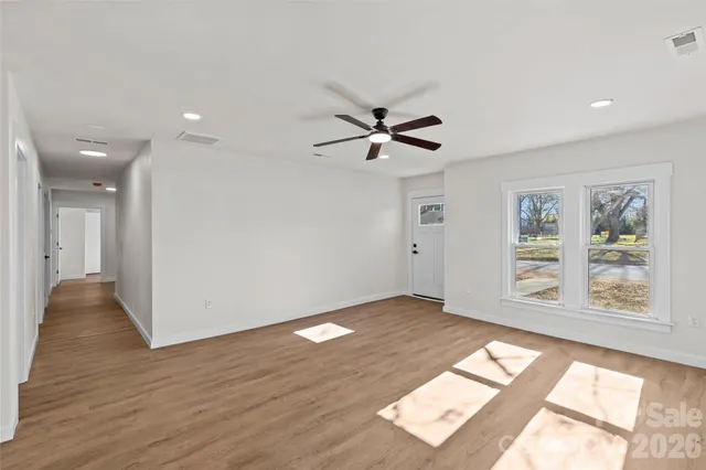 a view of an empty room with a window and wooden floor