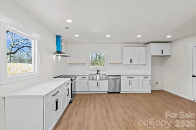 a kitchen with white cabinets and wooden floors