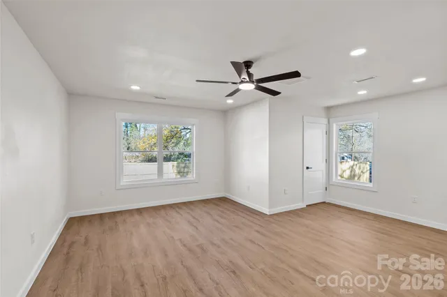 a view of an empty room with a window and wooden floor