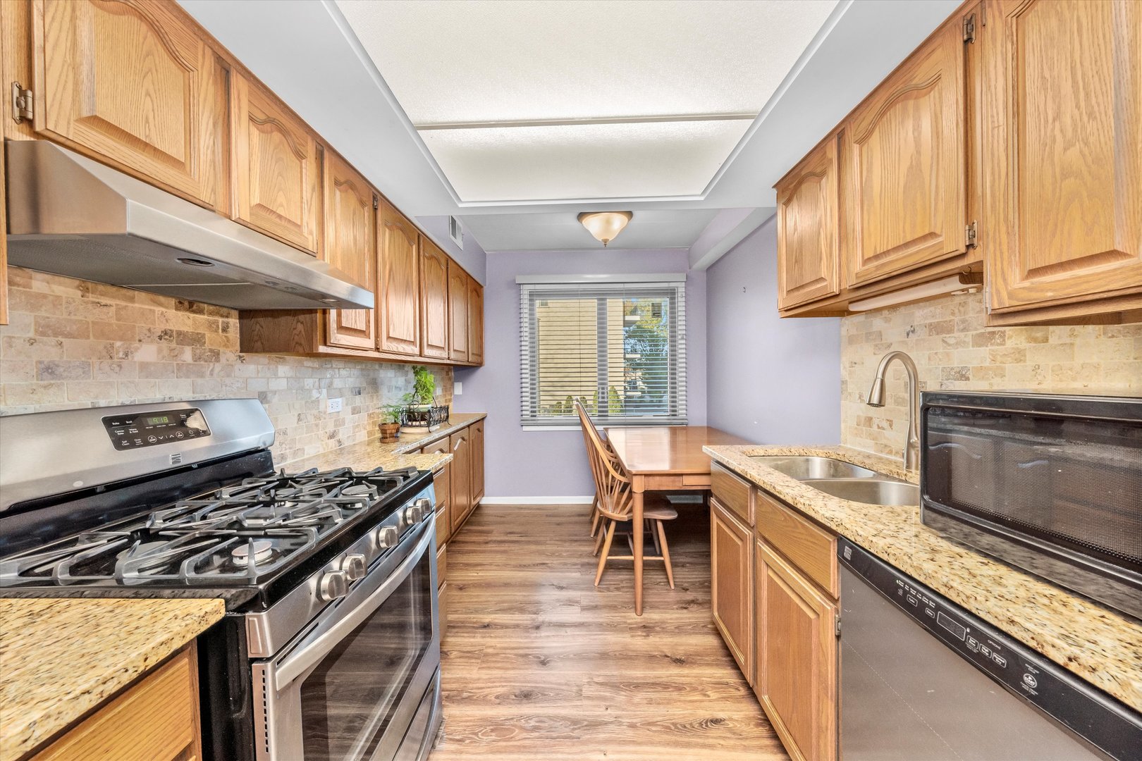 4530 West 93rd Street, Unit 1A Oak Lawn, IL 60453 - Photo 4 of 18 a kitchen with stainless steel appliances granite countertop a stove top oven a sink dishwasher and cabinets with wooden floor