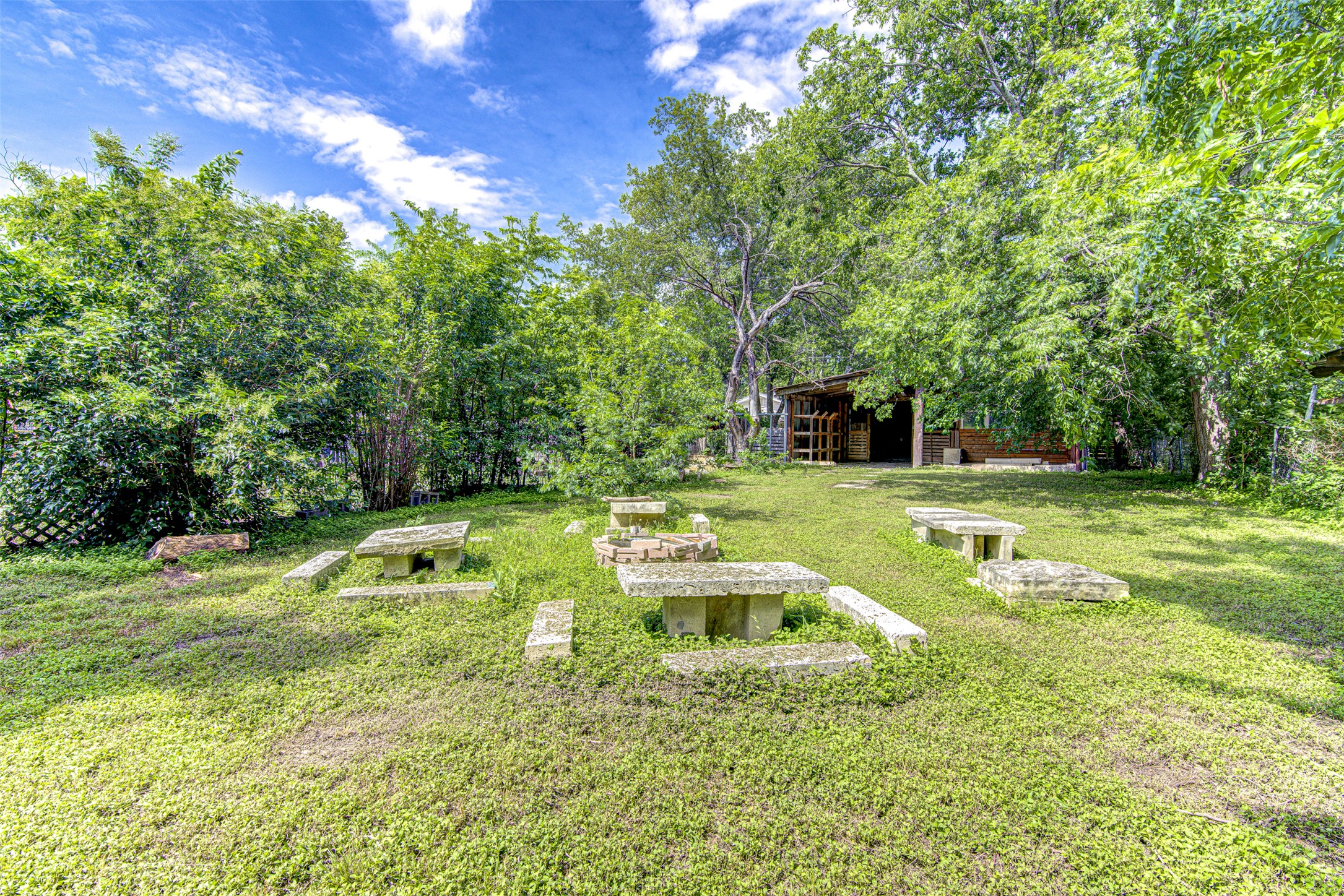 1807 San Jose Street Georgetown, TX 78626 - Photo 17 of 21 A verdant backyard retreat features a fire pit surrounded by stone benches, ideal for outdoor gatherings.