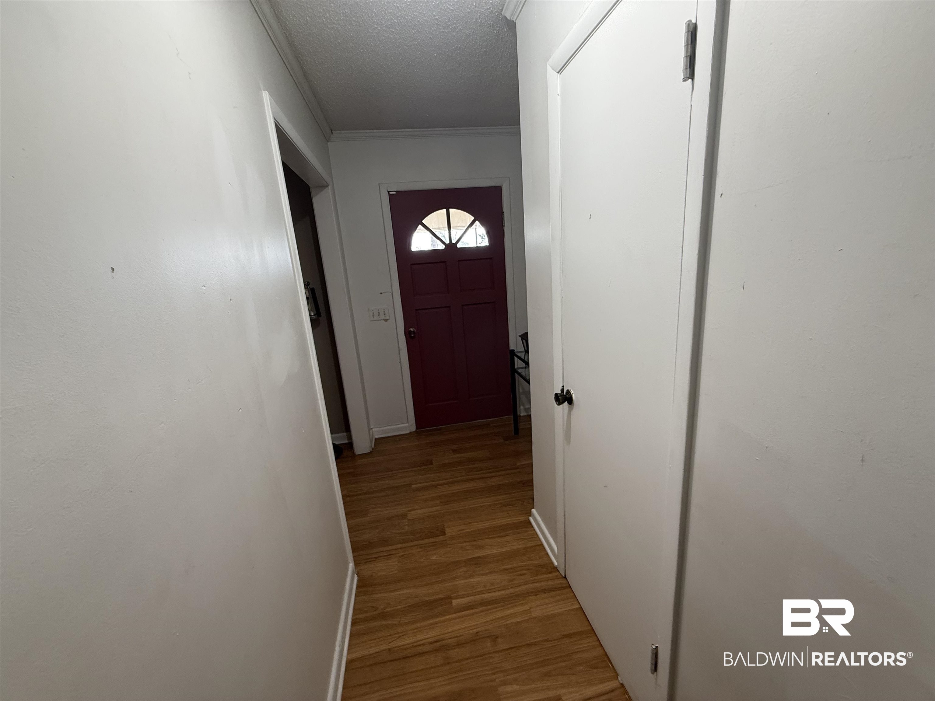 2807 Pea Ridge Road Brewton, AL 36426 - Photo 6 of 12 Doorway featuring a textured ceiling, ornamental molding, and wood finished floors