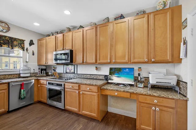 a kitchen with stainless steel appliances granite countertop a stove a sink and white cabinets with wooden floor