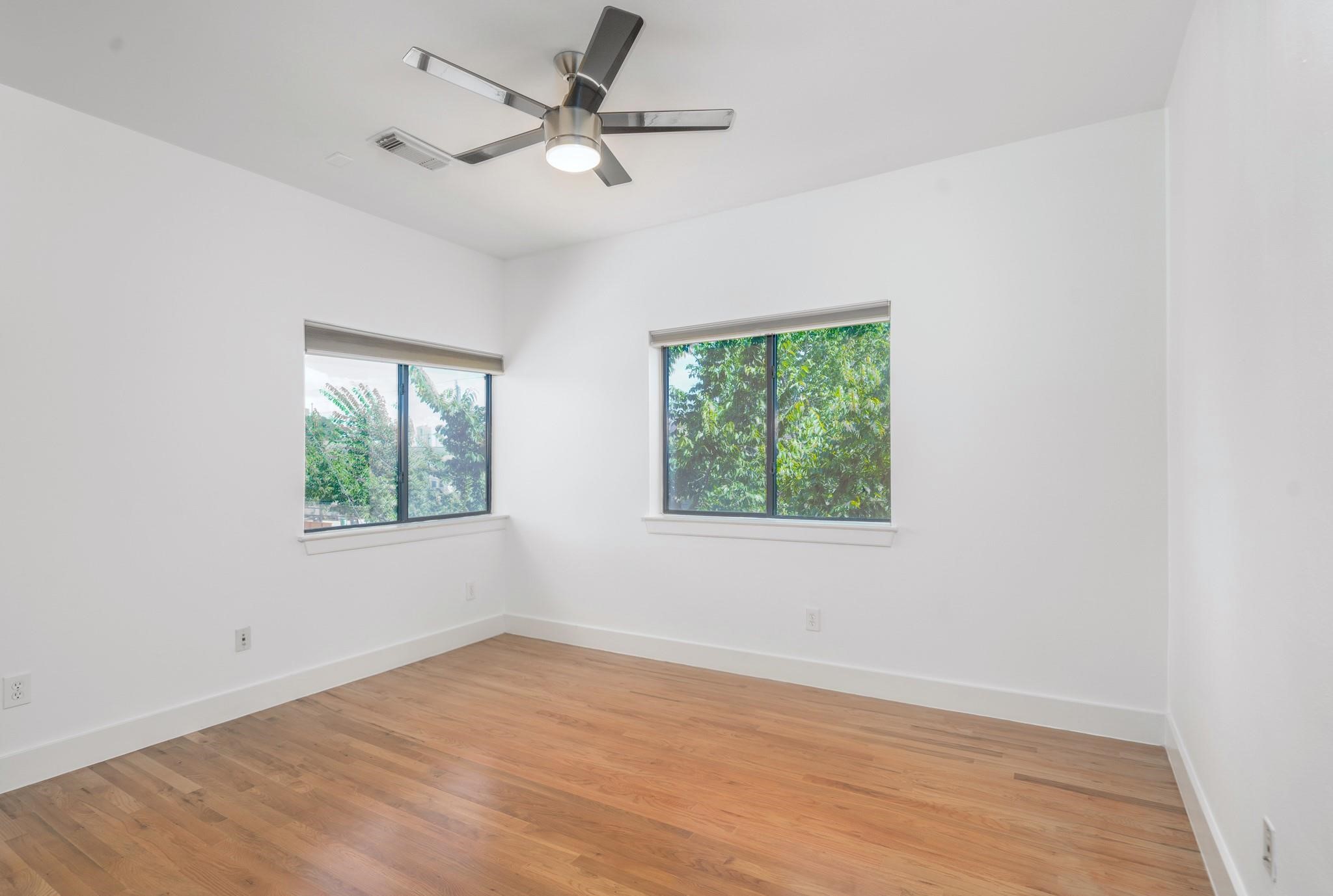 4302 Spencer Street Houston, TX 77007 - Photo 11 of 21 an empty room with wooden floor ceiling fan and windows