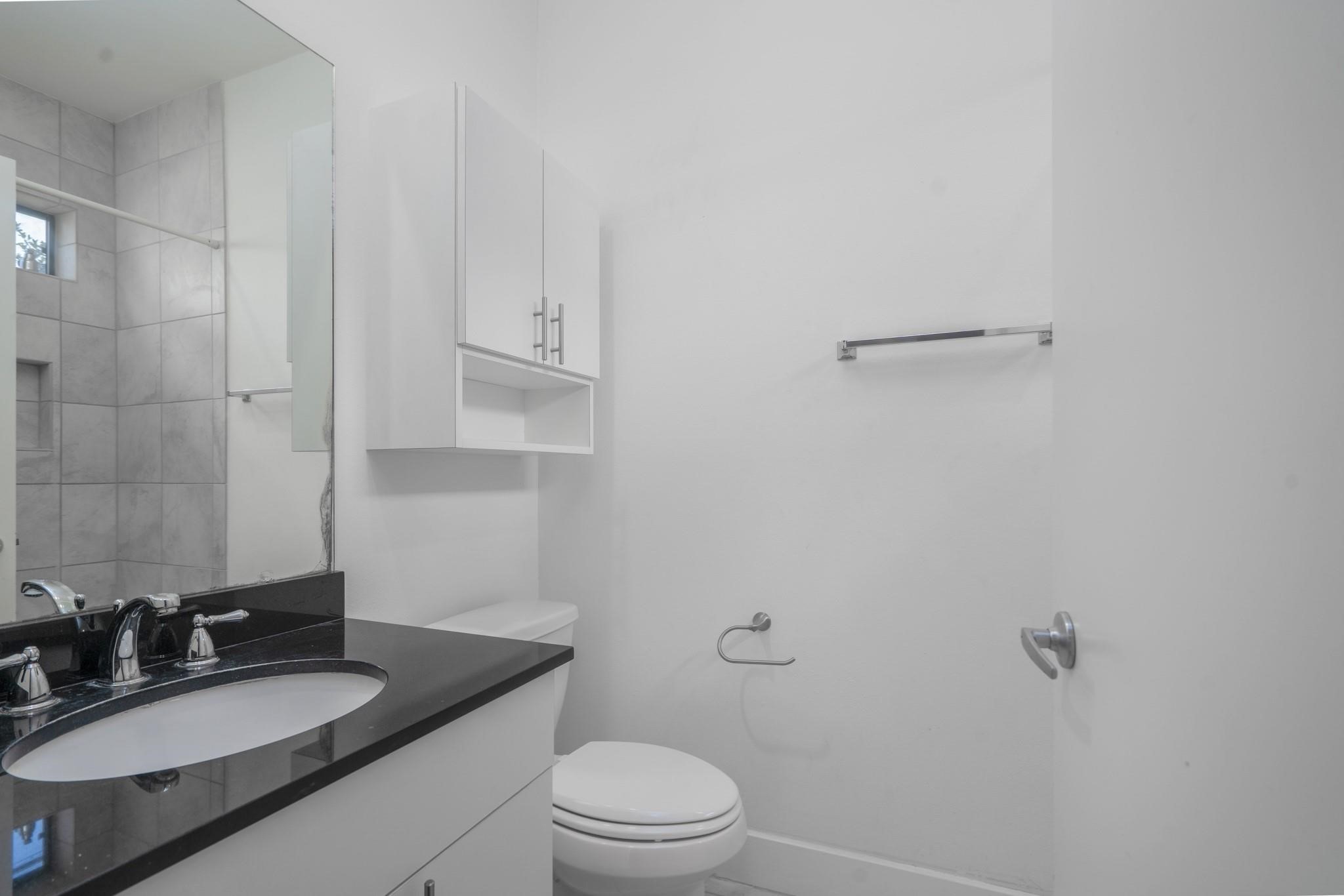 4302 Spencer Street Houston, TX 77007 - Photo 13 of 21 a bathroom with a granite countertop sink toilet a mirror and shower