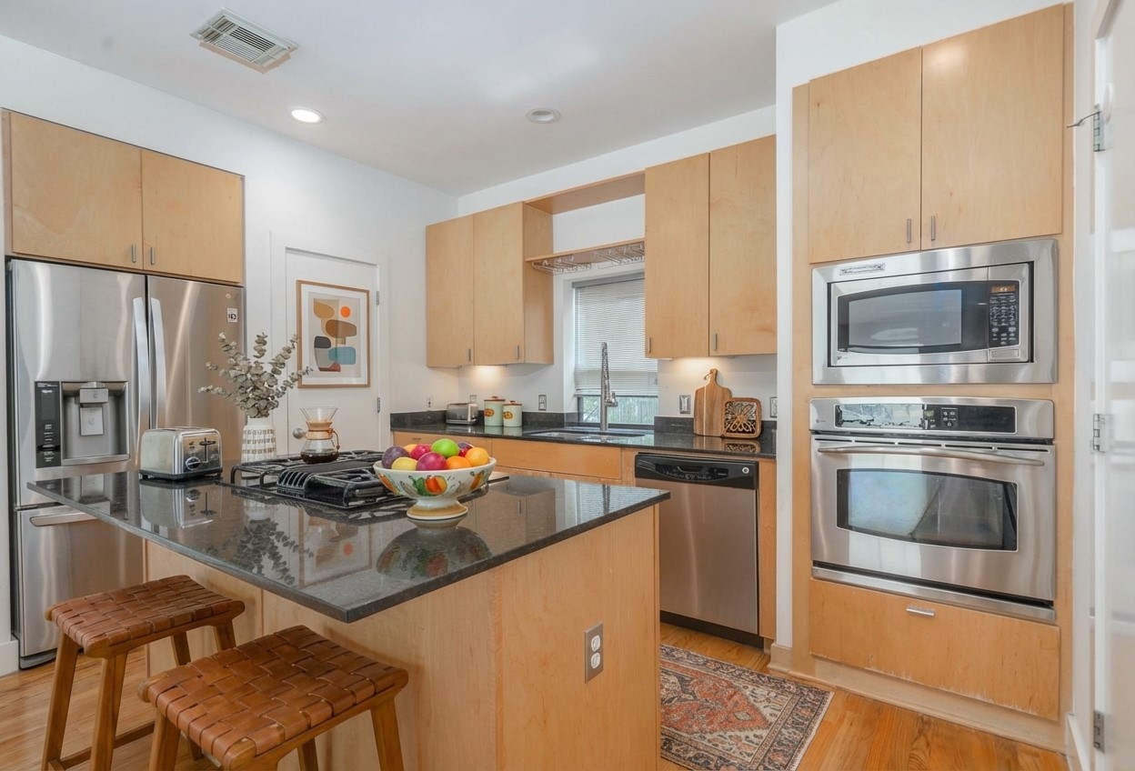 4302 Spencer Street Houston, TX 77007 - Photo 5 of 21 a kitchen with stainless steel appliances granite countertop a stove top oven a sink a refrigerator white cabinets and wooden floor