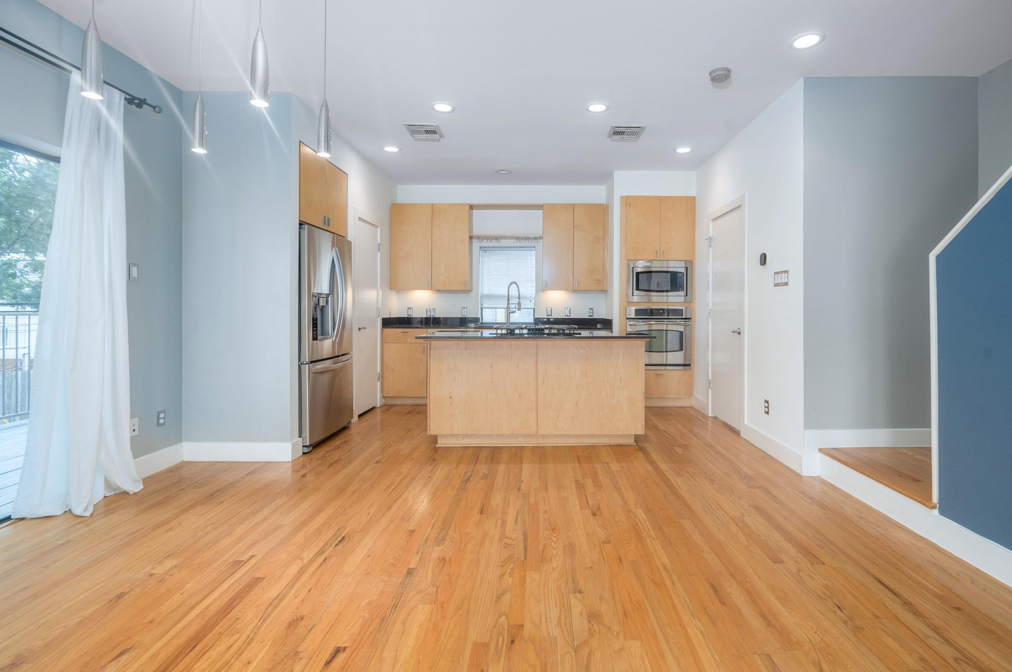4302 Spencer Street Houston, TX 77007 - Photo 6 of 21 a kitchen with stainless steel appliances granite countertop a refrigerator a stove a sink and white cabinets with wooden floor