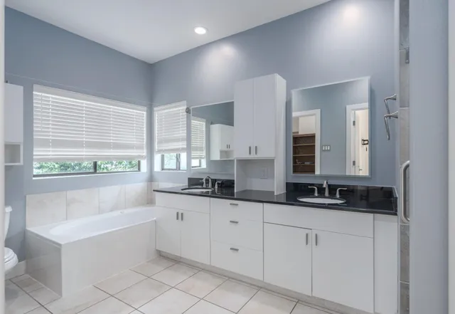 a bathroom with a double vanity sink a bathtub and mirror
