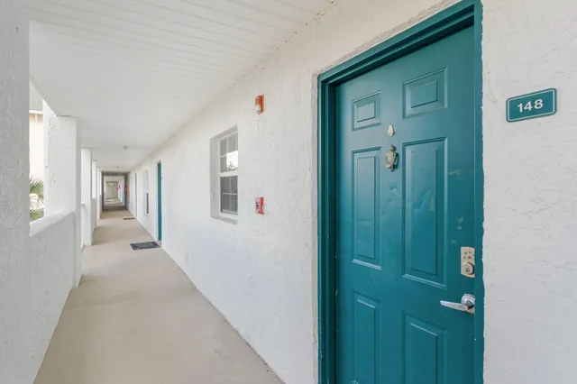a view of a hallway with wooden floor and a bathroom