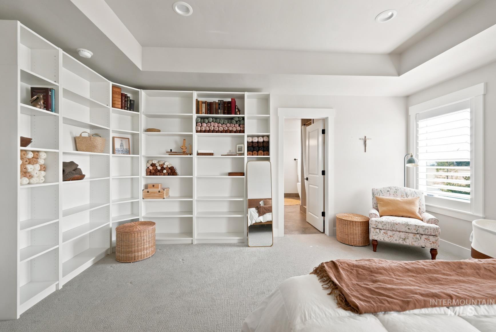 6933 South Zenith Avenue Meridian, ID 83642 - Photo 25 of 34 Recessed lighting illuminates a room featuring extensive built-in white shelving, a tray ceiling, and a large window with white louvered blinds