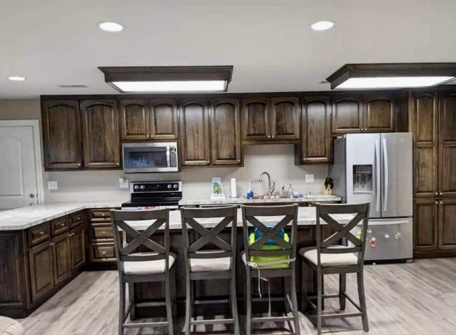 a kitchen with stainless steel appliances a table chairs refrigerator and cabinets
