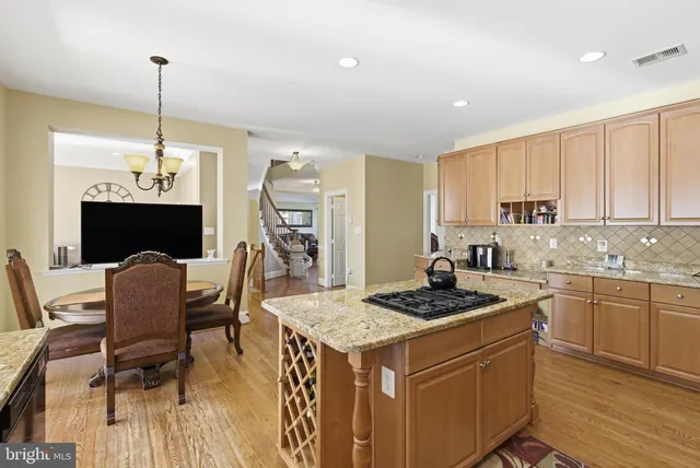 a kitchen with kitchen island granite countertop a stove a sink a dining table and chairs