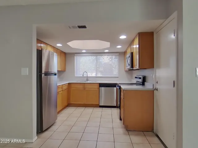 a view of a refrigerator in kitchen and an empty room
