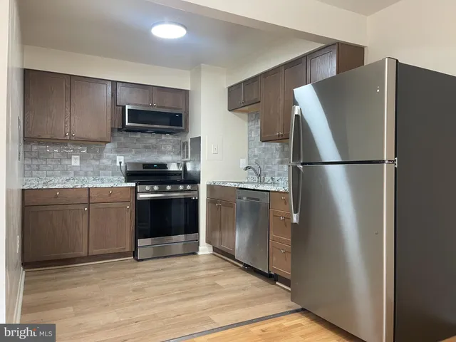 a kitchen with stainless steel appliances granite countertop a refrigerator and a stove top oven