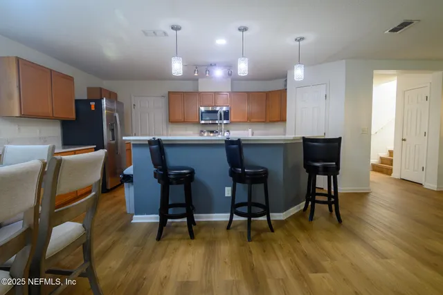 a kitchen with stainless steel appliances granite countertop a table chairs sink refrigerator and cabinets