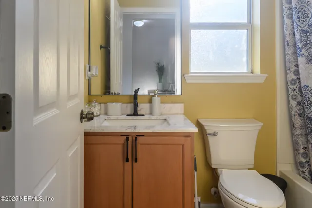 a bathroom with a granite countertop toilet sink and mirror