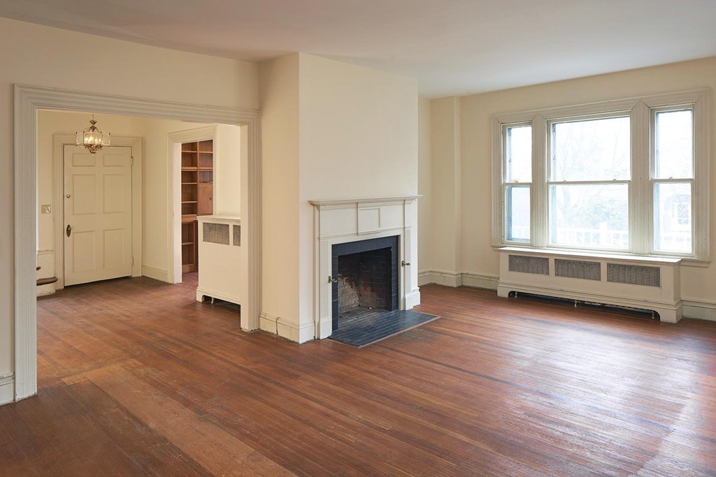 115 Windermere Road Newton, MA 02466 - Photo 2 of 8 an empty room with wooden floor a fireplace and windows