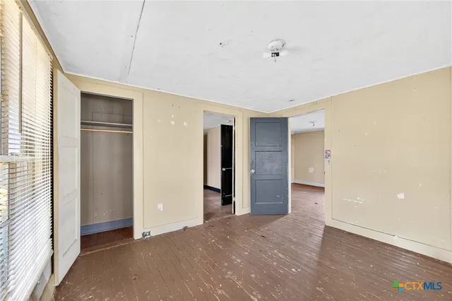 a view of an empty room with closet and a window