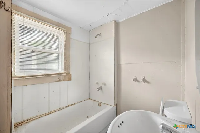 a bathroom with a bathtub toilet and window