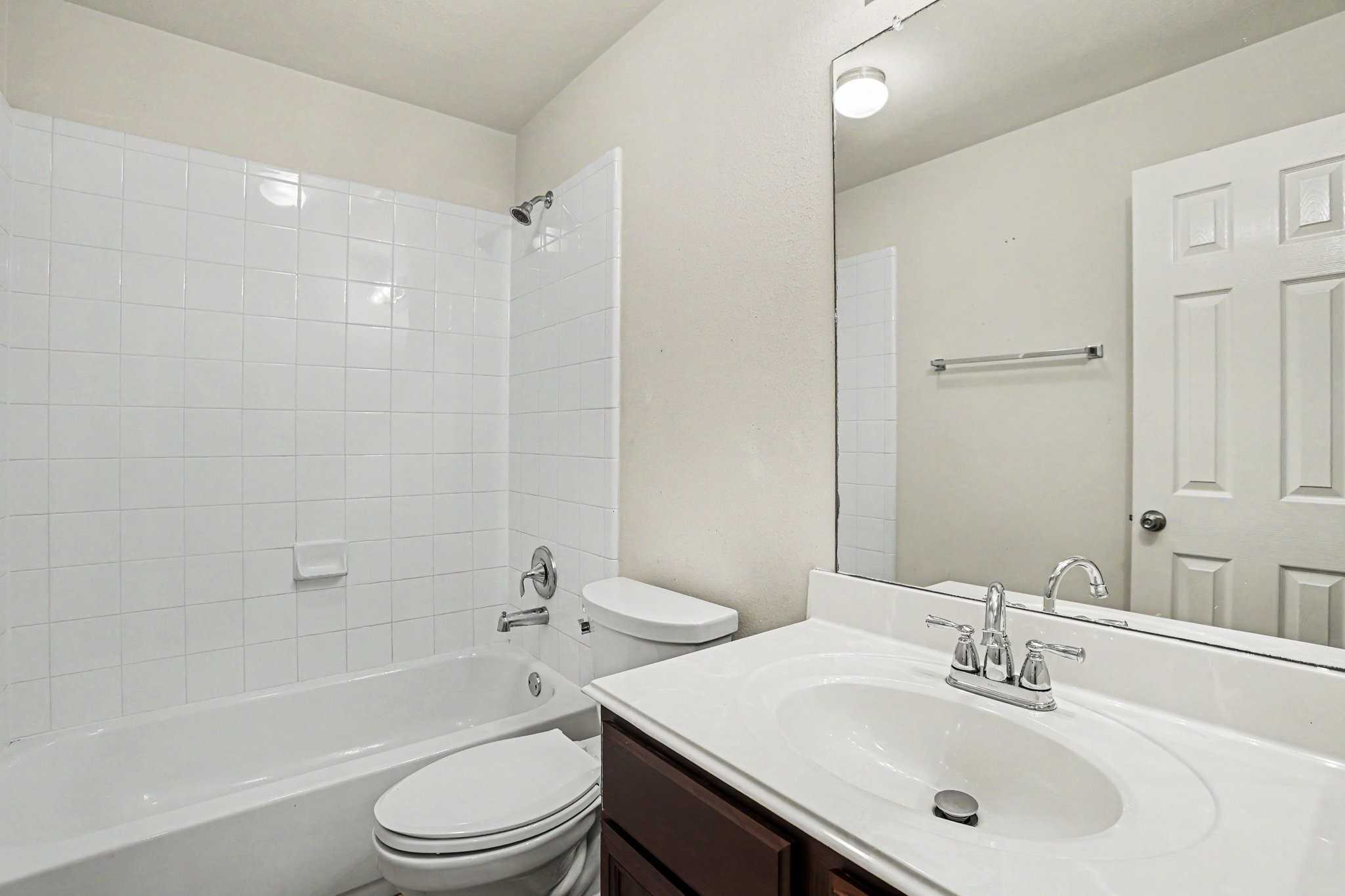 25222 Ginger Ranch Drive Katy, TX 77494 - Photo 29 of 33 Second bathroom features a clean, modern design with a white-tiled shower and bathtub combo, a sleek vanity with a large mirror, and a neutral color palette.