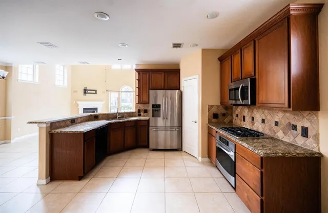 a large kitchen with stainless steel appliances granite countertop a stove top oven a sink dishwasher and a refrigerator
