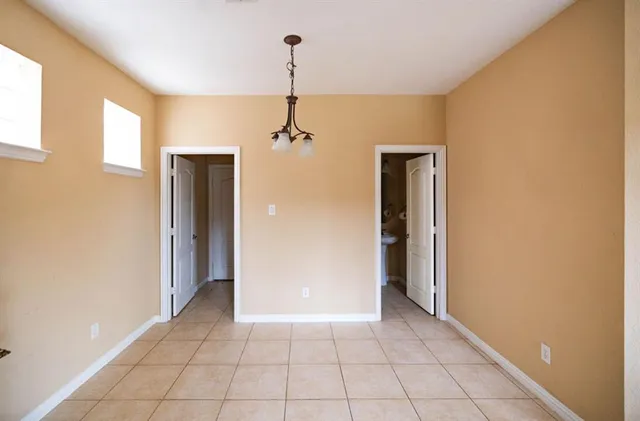 a view of an empty room with window and chandelier