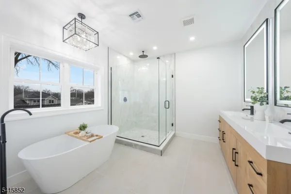 a bathroom with a tub sink shower and mirror