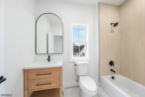 a bathroom with a toilet sink vanity tub and mirror
