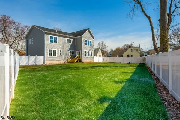 a view of a house with a big yard and large trees