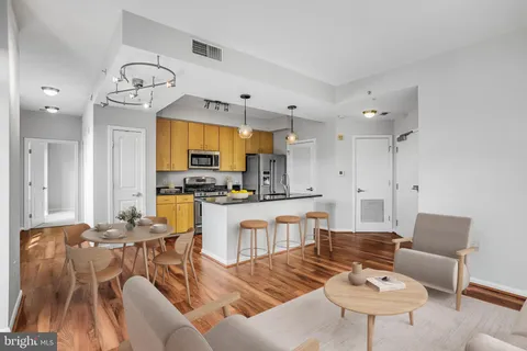 a living room with furniture kitchen view and a chandelier