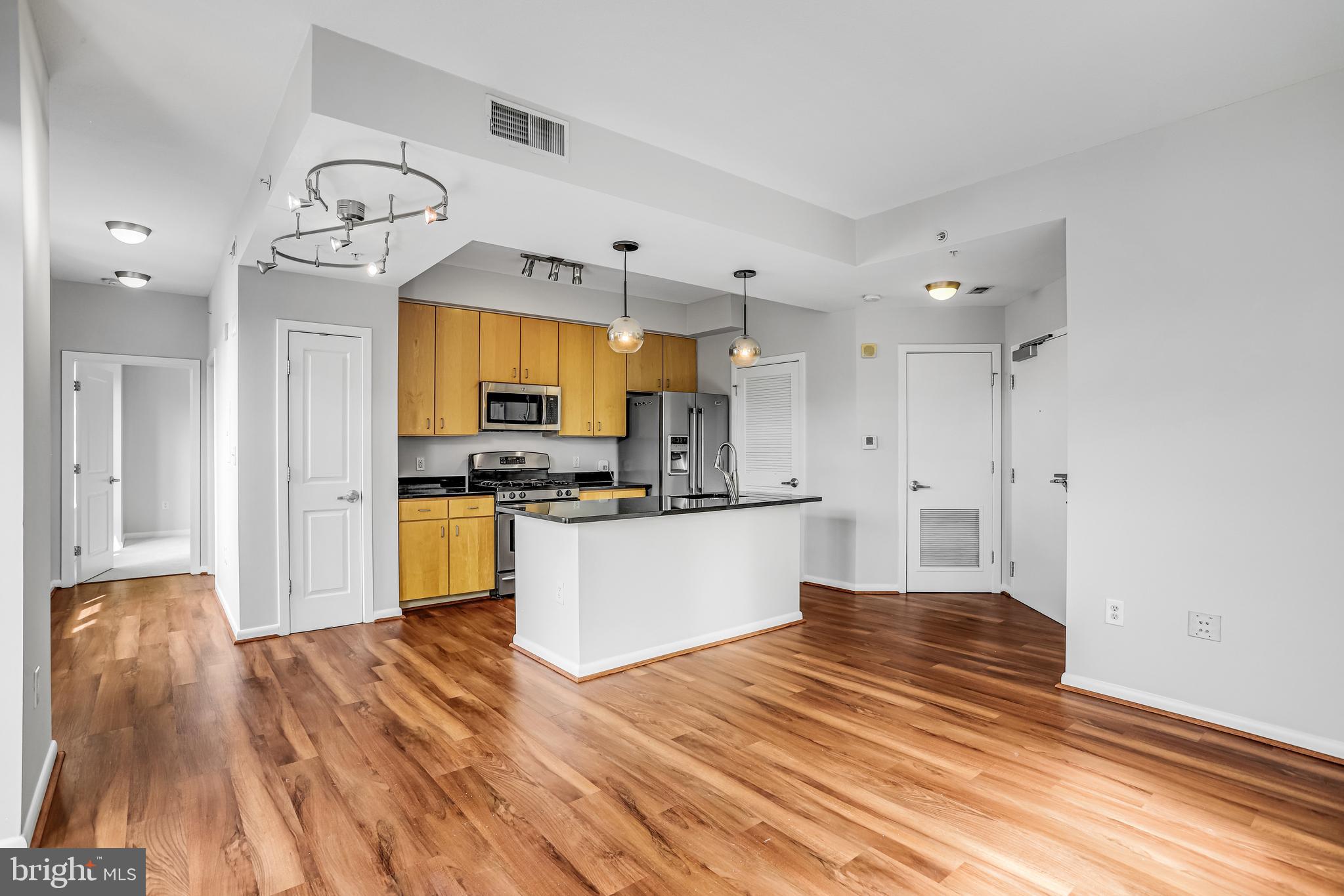 1001 L Street Northwest, Unit 811 Washington, DC 20001 - Photo 15 of 45 a large kitchen with cabinets wooden floor and stainless steel appliances