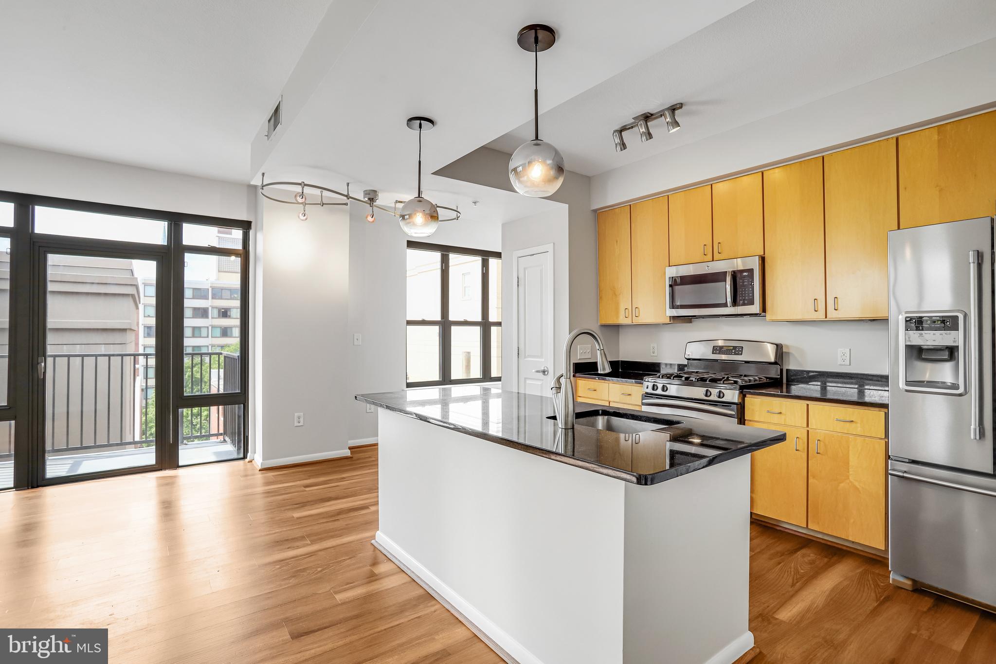 1001 L Street Northwest, Unit 811 Washington, DC 20001 - Photo 4 of 45 a kitchen with stainless steel appliances granite countertop a refrigerator a stove a sink dishwasher a oven with a dining table and chairs with wooden floor